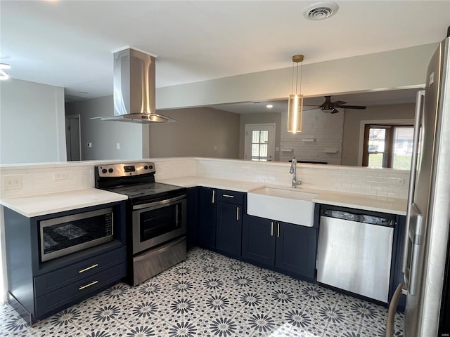 kitchen with kitchen peninsula, sink, tasteful backsplash, island exhaust hood, and stainless steel appliances