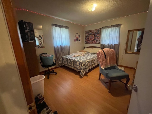 bedroom with hardwood / wood-style flooring, multiple windows, and a textured ceiling