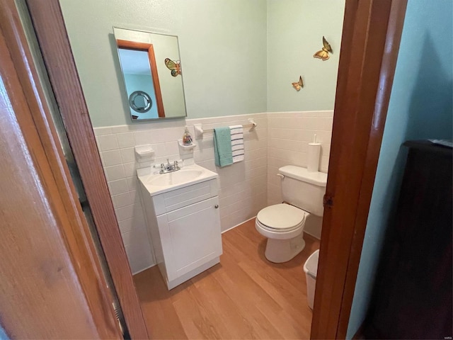 bathroom with tile walls, hardwood / wood-style floors, vanity, and toilet