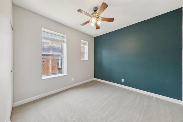 unfurnished room with carpet floors, baseboards, and a ceiling fan