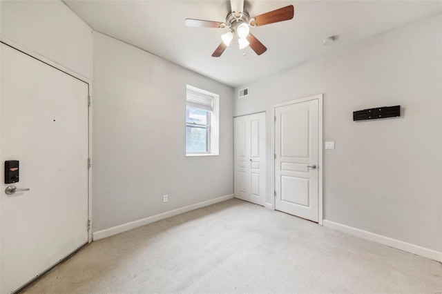 unfurnished bedroom featuring baseboards, ceiling fan, visible vents, and light colored carpet