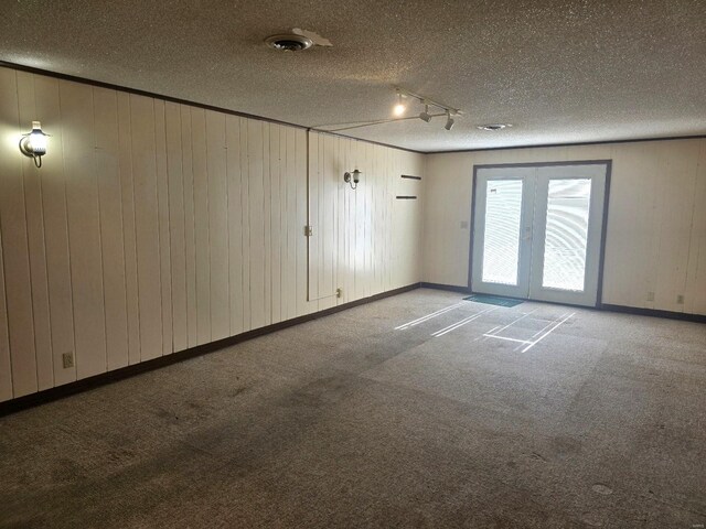 unfurnished room with rail lighting, a textured ceiling, and carpet flooring