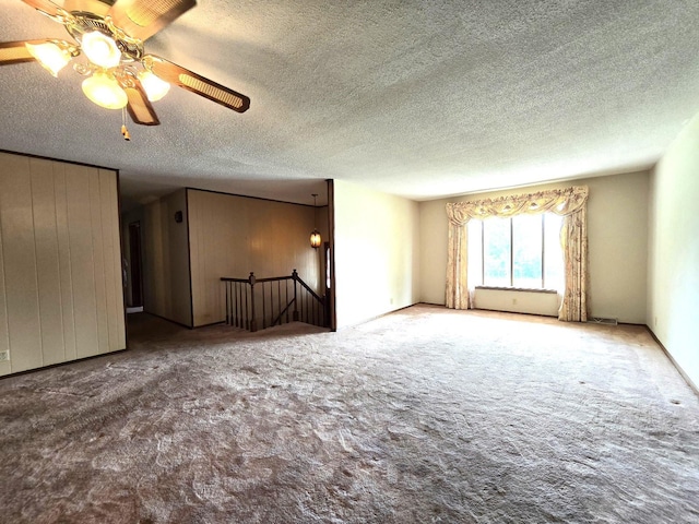 carpeted spare room featuring a textured ceiling and ceiling fan