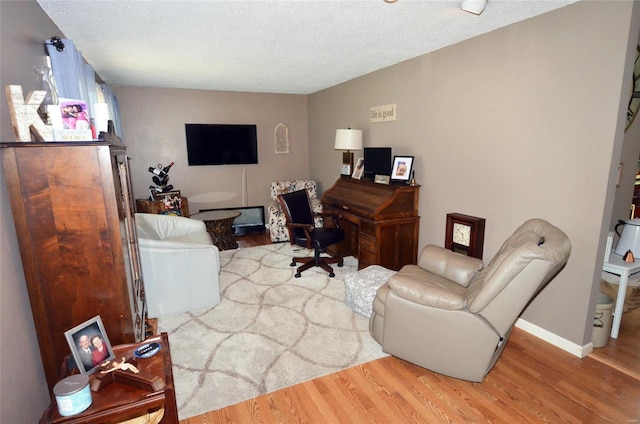 home office with light hardwood / wood-style flooring and a textured ceiling