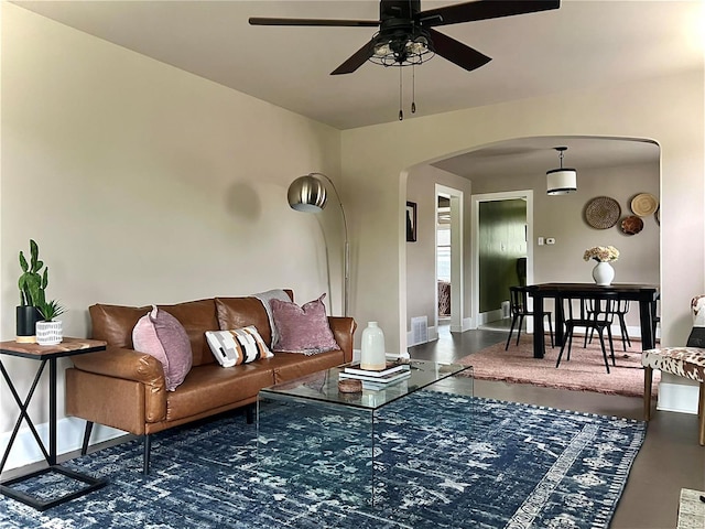 living room with a ceiling fan, visible vents, arched walkways, and baseboards