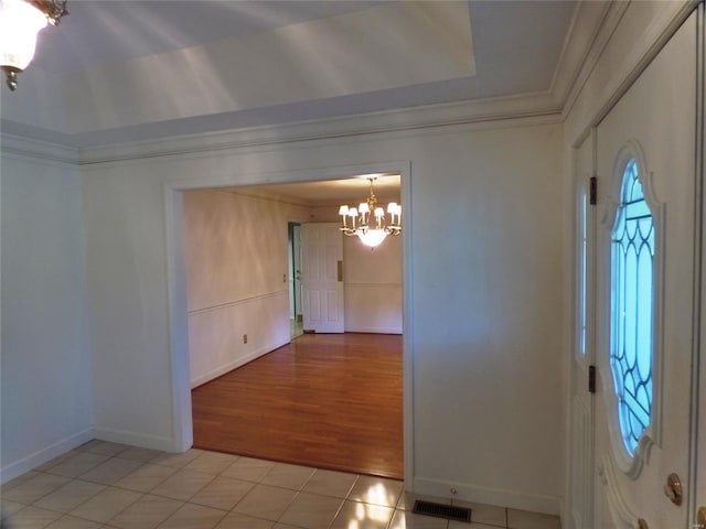 entryway featuring crown molding, a chandelier, and light tile patterned flooring