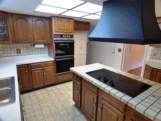 kitchen with black appliances, light tile patterned flooring, tile countertops, and decorative backsplash