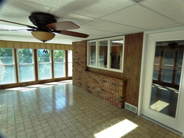 interior space featuring ceiling fan and a drop ceiling