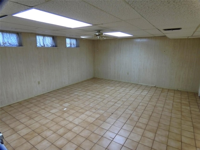 basement featuring ceiling fan, light tile patterned flooring, and a drop ceiling