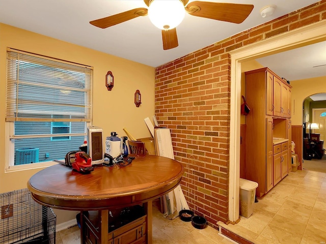 tiled dining space featuring brick wall and ceiling fan