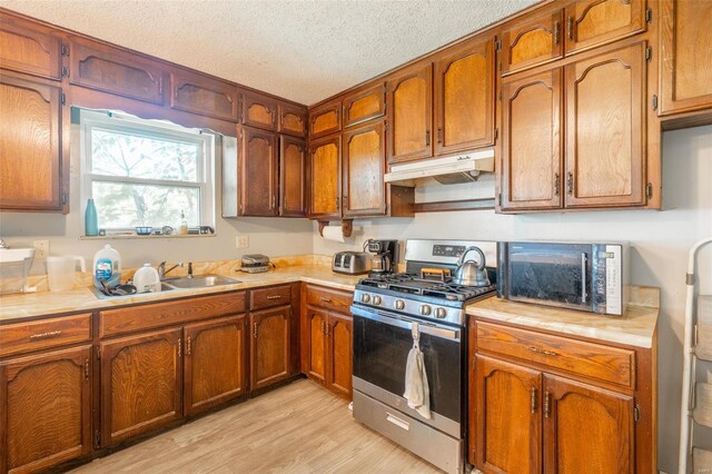 kitchen with sink, light hardwood / wood-style flooring, a textured ceiling, and gas stove