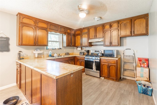 kitchen featuring appliances with stainless steel finishes, light hardwood / wood-style flooring, a textured ceiling, sink, and kitchen peninsula