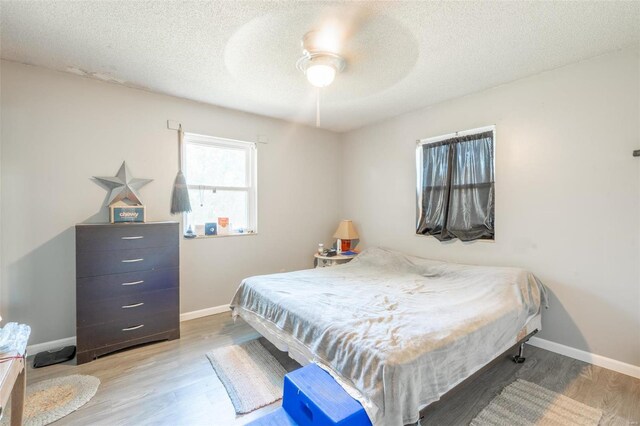 bedroom with ceiling fan, hardwood / wood-style floors, and a textured ceiling