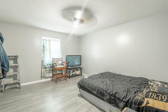 bedroom with light wood-type flooring, ceiling fan, and a textured ceiling