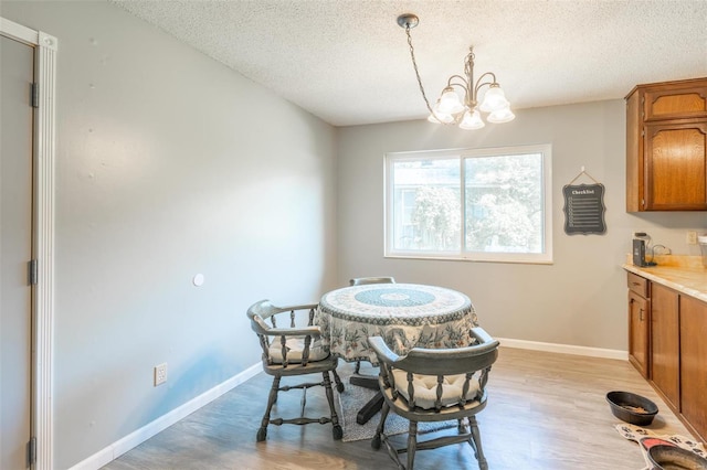 dining area with a notable chandelier, light hardwood / wood-style flooring, and a textured ceiling