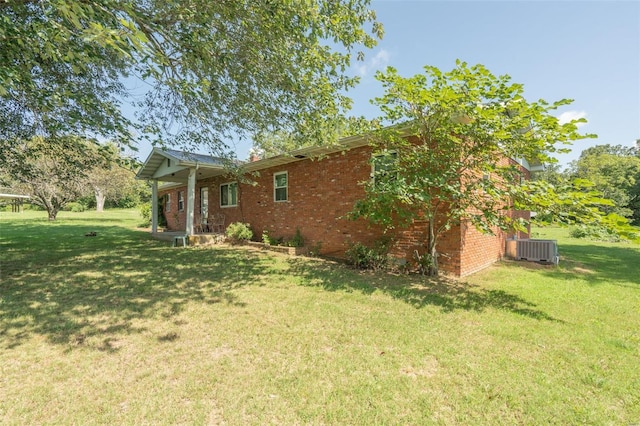 view of side of home with central AC unit and a yard