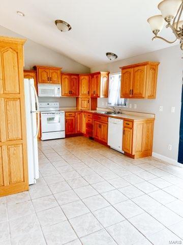 kitchen featuring a chandelier, white appliances, vaulted ceiling, and light tile patterned floors