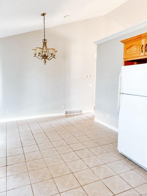 empty room featuring light tile patterned floors, an inviting chandelier, and vaulted ceiling