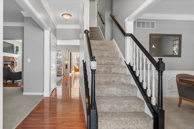 stairway with crown molding, a fireplace, and carpet flooring