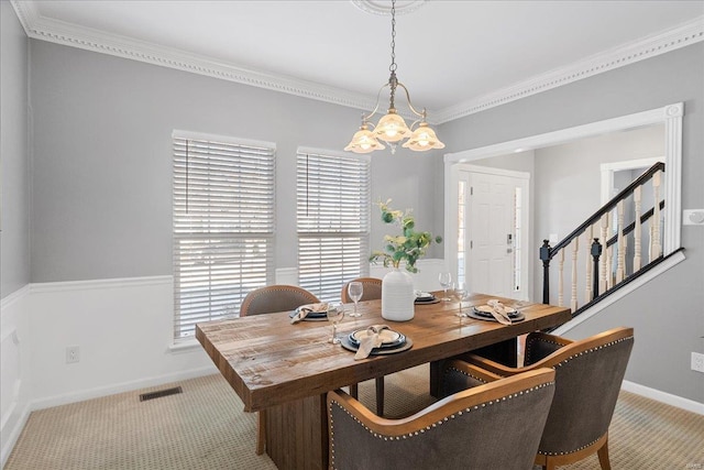 carpeted dining space with an inviting chandelier and crown molding