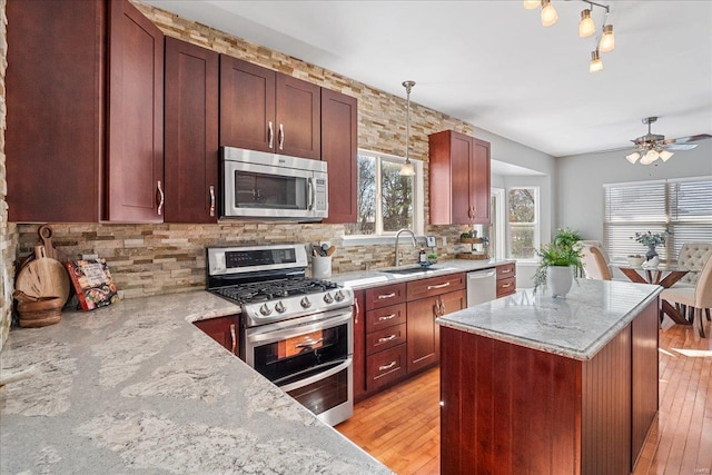 kitchen with light stone counters, hanging light fixtures, tasteful backsplash, and appliances with stainless steel finishes