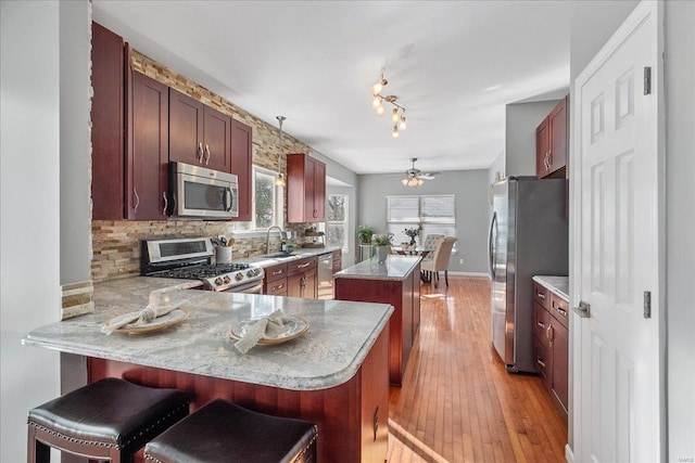 kitchen with backsplash, stainless steel appliances, kitchen peninsula, and a breakfast bar