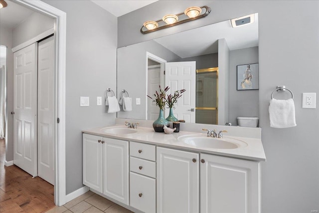 bathroom featuring tile patterned floors, vanity, toilet, and a shower with door