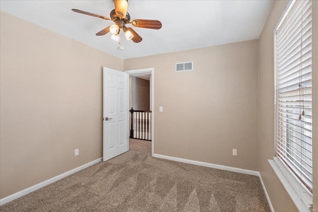 carpeted spare room with ceiling fan