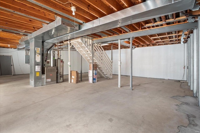 basement with gas water heater, heating unit, and electric panel