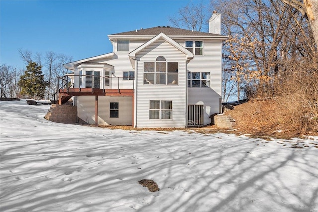 snow covered back of property with a wooden deck