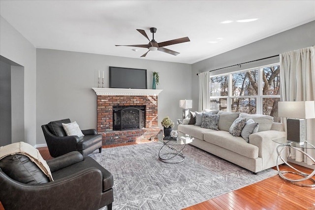 living room featuring ceiling fan, a fireplace, and hardwood / wood-style floors