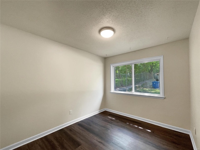 spare room featuring a textured ceiling and dark hardwood / wood-style floors