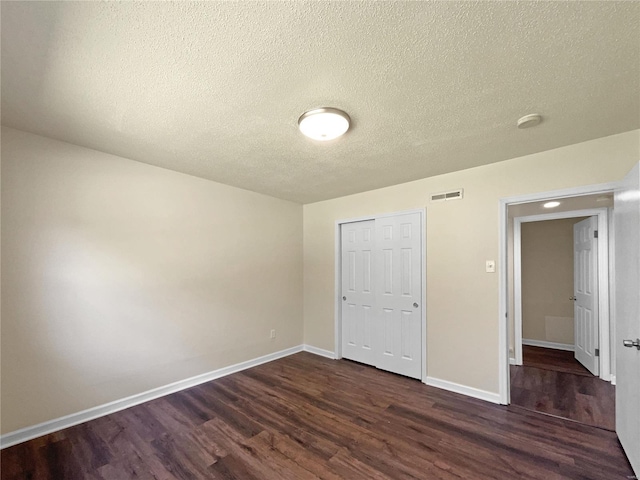 unfurnished bedroom with a closet, dark hardwood / wood-style flooring, and a textured ceiling