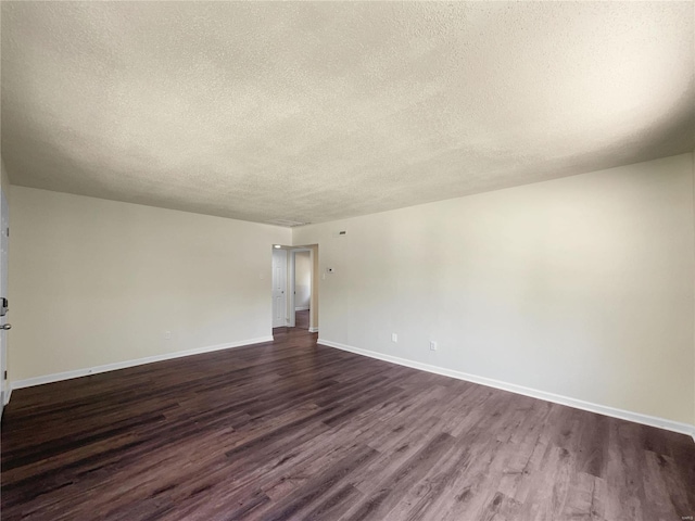 empty room with dark hardwood / wood-style flooring and a textured ceiling