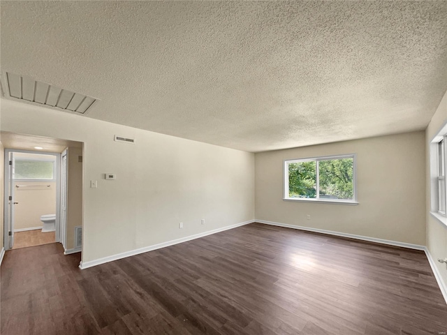 unfurnished room with dark hardwood / wood-style floors and a textured ceiling