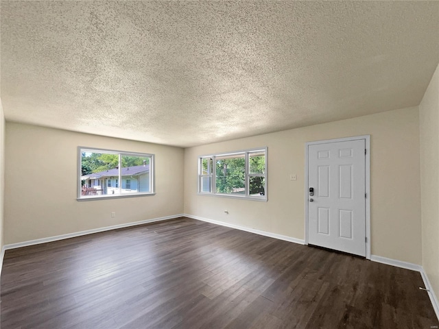 unfurnished room with a textured ceiling and dark hardwood / wood-style floors