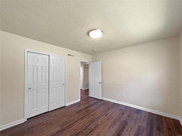 unfurnished bedroom featuring dark hardwood / wood-style floors, a textured ceiling, and a closet