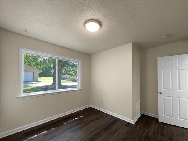 unfurnished room featuring a textured ceiling and dark hardwood / wood-style floors