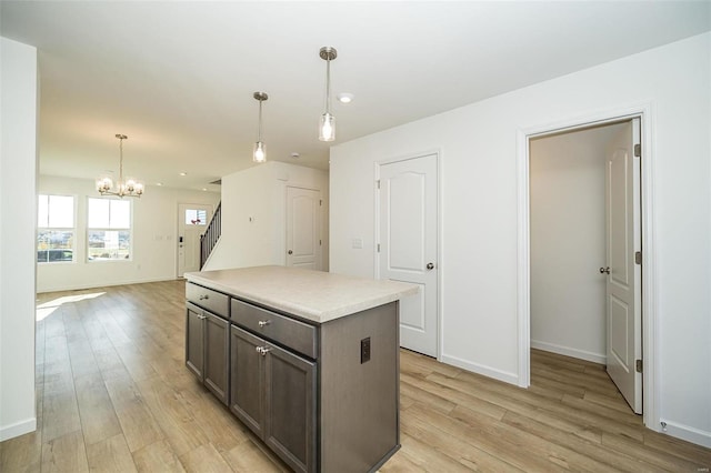 kitchen with dark brown cabinetry, a center island, a notable chandelier, light hardwood / wood-style floors, and decorative light fixtures