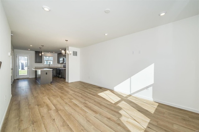 unfurnished living room featuring light hardwood / wood-style floors and an inviting chandelier