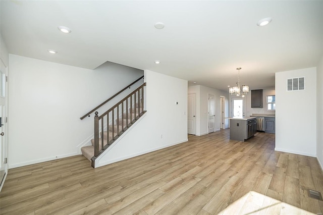 unfurnished living room with light hardwood / wood-style floors and an inviting chandelier