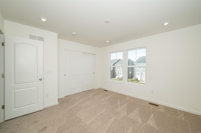 unfurnished bedroom with a closet and light colored carpet