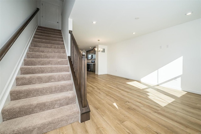 stairway with hardwood / wood-style floors and an inviting chandelier