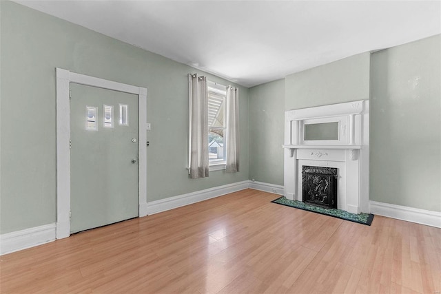 unfurnished living room with a fireplace, a wealth of natural light, and light wood-type flooring