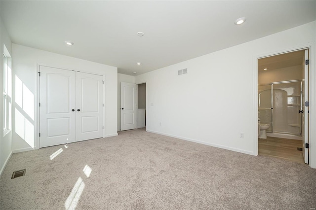 unfurnished bedroom with carpet, ensuite bath, and a closet