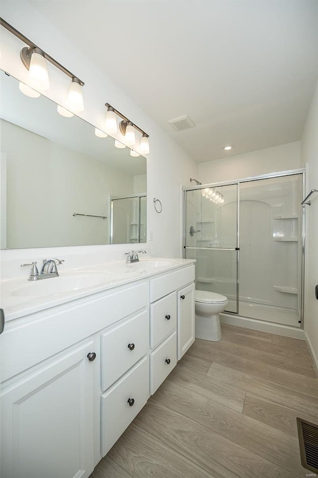 bathroom featuring hardwood / wood-style floors, vanity, an enclosed shower, and toilet