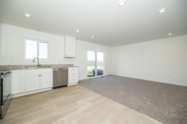 kitchen with sink, light stone counters, light colored carpet, white cabinets, and appliances with stainless steel finishes