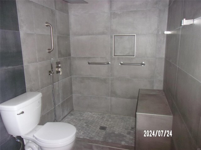 bathroom featuring a tile shower and toilet