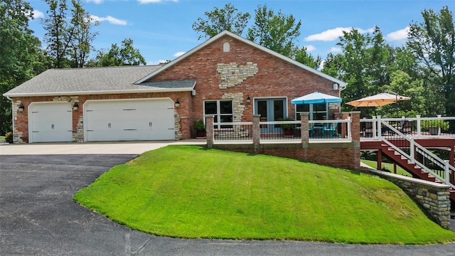 view of front of property with a deck, a garage, and a front yard