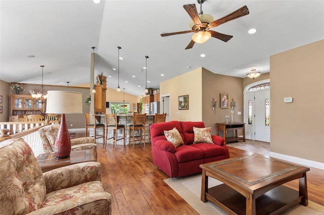 living room featuring lofted ceiling, light hardwood / wood-style floors, ceiling fan with notable chandelier, and a wealth of natural light